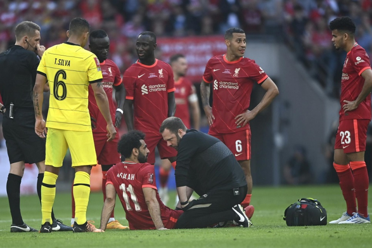 Sentado no gramado, cercado por jogadores do Liverpool e Thiago Silva, Salah é atendido por médico do clube