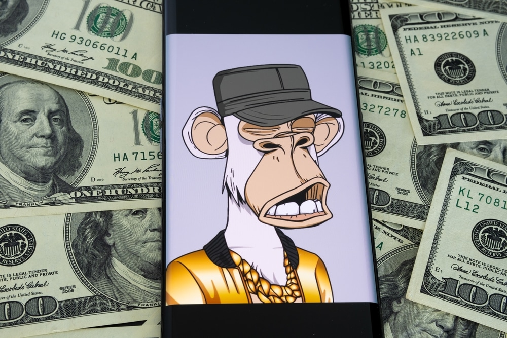NFT da coleção Bored Ape Yacht Club vista na tela de um smartphone com notas de dólares ao fundo