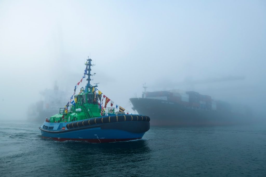 Rebocador elétrico sob neblina com outros barcos