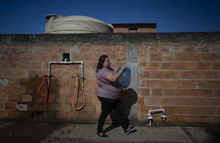 Na terra dos royalties. Gabriela Cristina Santos carrega galão abastecido em caixa d’água pública no bairro Lagomar