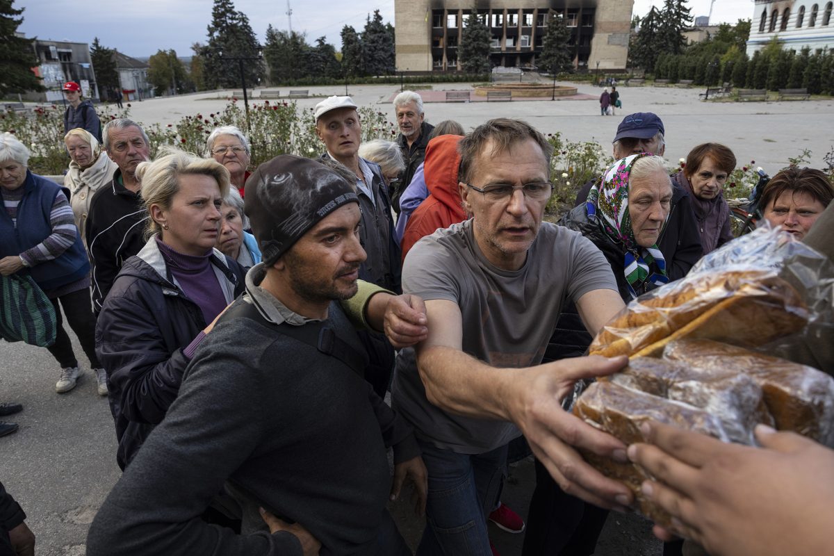 Residents grab bread as a local humanitarian organization, Good Bread, offers handouts on September 20, in Izium, Ukraine.