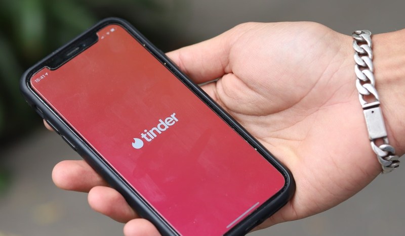 mão segurando smartphone com app do tinder