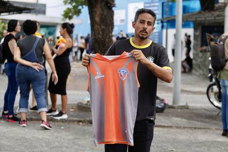 Robson de Araújo segura a camisa de futebol do filho, Alex Souza de Araújo Santos, de 19 anos, morto após ser baleado na Kelson's