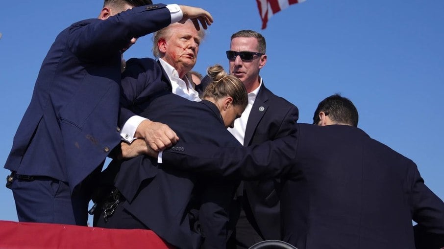 Trump é baleado em comício por jovem de 20 anos, posteriormente morto pelo Serviço Secreto Trump é baleado em comício por jovem de 20 anos, posteriormente morto pelo Serviço Secreto