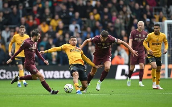 André (de amarelo) se estica para corta a bola que está sendo disputada entre ele, Ruben Dias e Bernardo Silva André (de amarelo) se estica para corta a bola que está sendo disputada entre ele, Ruben Dias e Bernardo Silva