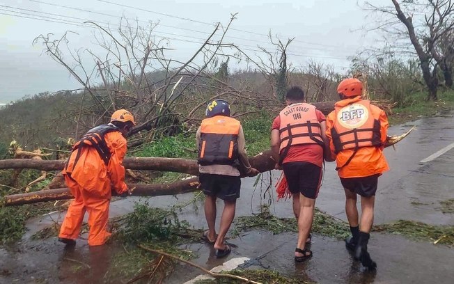 Funcionários da Guarda Costeira retiram árvores de estrada bloqueada na cidade filipina de Gigmoto Funcionários da Guarda Costeira retiram árvores de estrada bloqueada na cidade filipina de Gigmoto