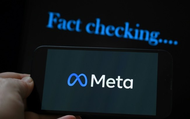 Esta ilustração fotográfica criada em 8 de janeiro de 2025, em Bruxelas, mostra o logotipo da gigante da mídia Meta exibido em um smartphone e uma tela com as palavras “verificação de fatos”