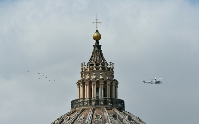 Foto tirada em Roma em 23 de abril de 2025 mostra um helicóptero da polícia italiana perto da cúpula da Basílica de São Pedro, no Vaticano, onde está exposto o caixão com o corpo do papa Francisco, que morreu na segunda-feira, 21 de abril
