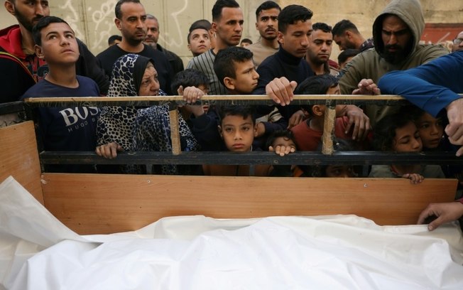 Palestinos obsercam corpos antes do traslado para enterro em Jabaliya, norte da Faixa de Gaza, em 16 de abril de 2025