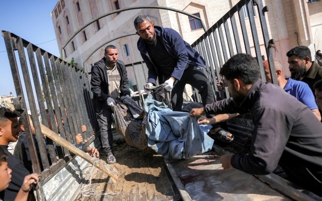 Um grupo de pessoas carrega o corpo de uma vítima de um bombardeio em Jabaliya, Faixa de Gaza, 18 de abril de 2025