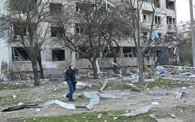 Um homem caminha em frente a um prédio danificado por bombardeios em Kharkiv, na Ucrânia, em 18 de abril de 2025