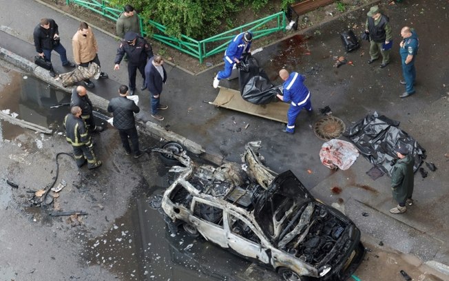 Policiais russos e funcionários do serviço funerário ao lado de carro destruído por um artefato explosivo em Balashikha, a leste de Moscou, em 25 de abril de 2025 Policiais russos e funcionários do serviço funerário ao lado de carro destruído por um artefato explosivo em Balashikha, a leste de Moscou, em 25 de abril de 2025