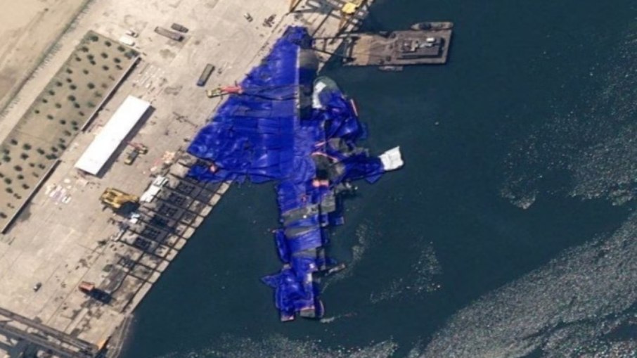 O navio de guerra tombado no estaleiro foi coberto com uma lona azul O navio de guerra tombado no estaleiro foi coberto com uma lona azul