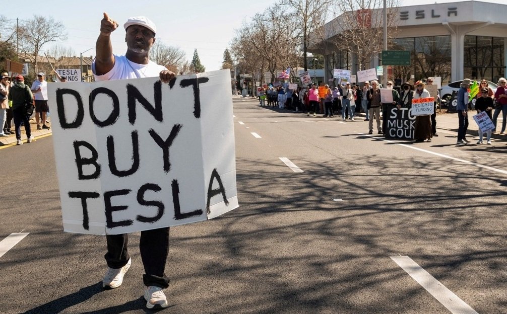 Pessoas protestam contra a Tesla e Elon Musk do lado de fora de uma concessionária Tesla em Palo Alto, Califórnia, EUA, em 8 de março de 2025