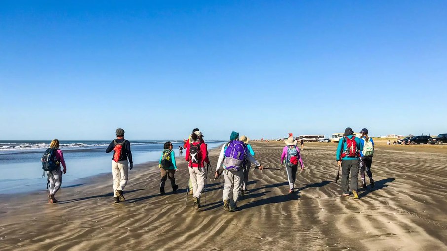 Aventureiros atravessam a extensão da praia andando Aventureiros atravessam a extensão da praia andando