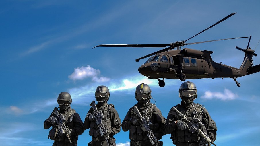 Soldados armados e helicóptero ao fundo Soldados armados e helicóptero ao fundo