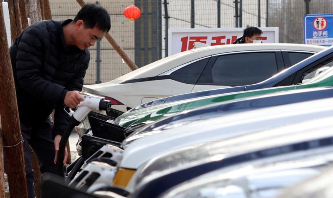 Um homem recarrega um carro em uma estação de carregamento de veículos elétricos em Pequim, China, em 2 de fevereiro de 2024