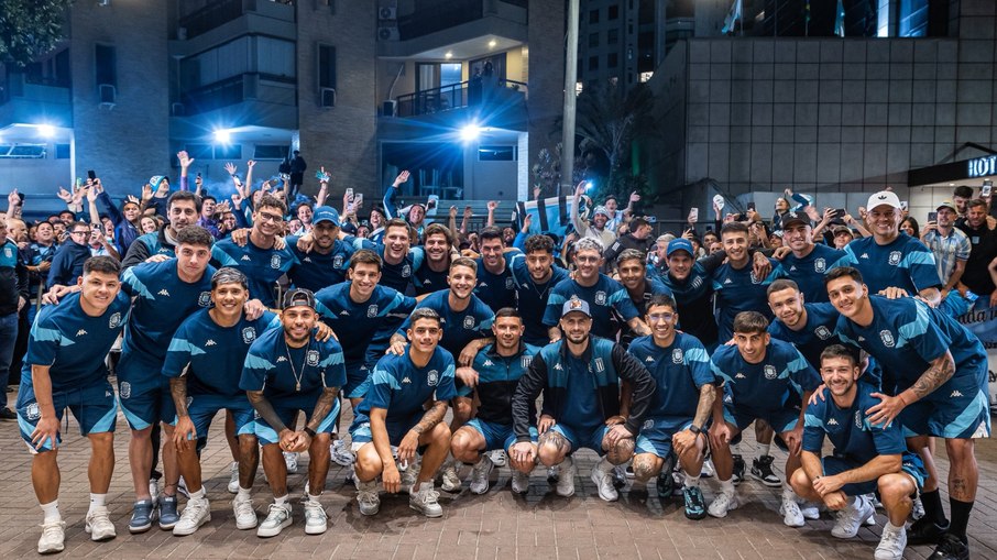 Elenco do Racing tira foto com torcedores ao fundo na porta do hotel no Rio