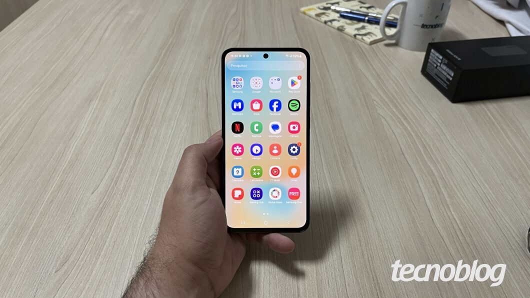 M&atilde;o segurando Galaxy S24 FE na tela de aplicativos