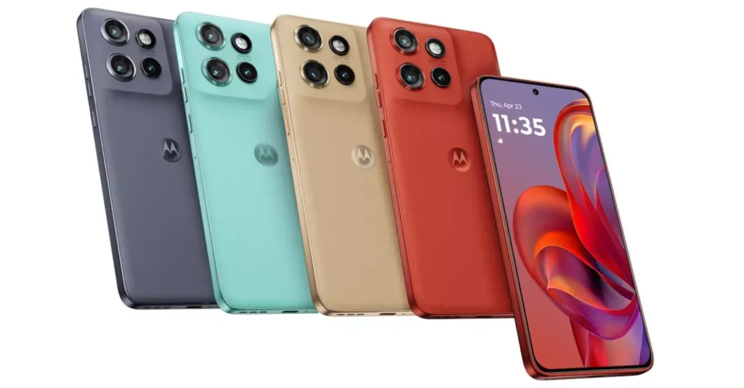 Foto de est&uacute;dio em fundo branco exibindo cinco smartphones em diferentes cores, dispostos lado a lado, em diagonal. O modelo &eacute; o mesmo para todos. Da esquerda para a direita, os aparelhos t&ecirc;m a traseira nas cores: roxo-escuro, verde-&aacute;gua, dourado (ou bege), e vermelho-tijolo. Todos exibem o logo da Motorola e um grande m&oacute;dulo de c&acirc;mera com tr&ecirc;s lentes