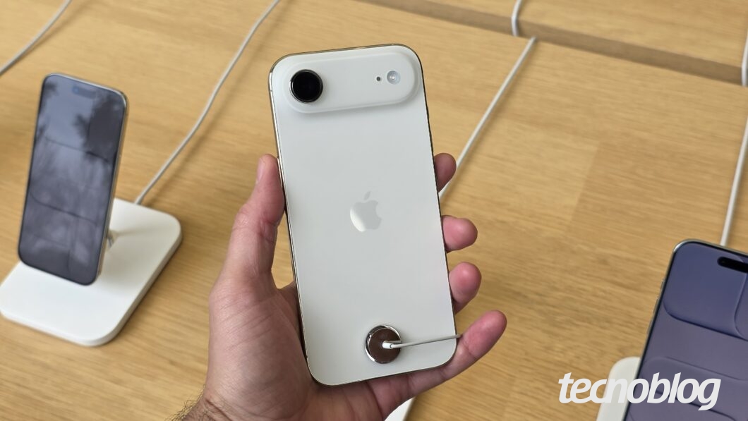 Imagem mostra um iPhone Air branco sendo segurado em uma mão. O modelo está virado com a parte traseira para a câmera.