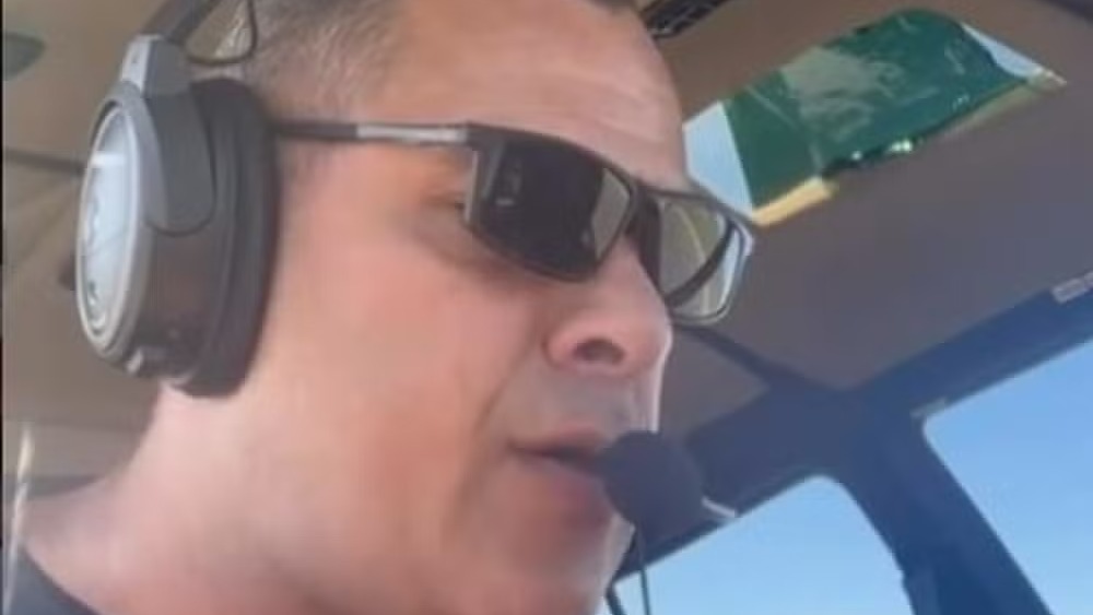 Piloto usando óculos de sol e headset com microfone em cabine de helicóptero